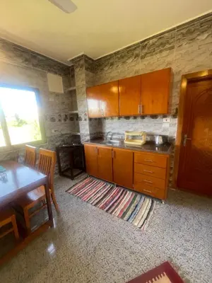 a kitchen with wooden cabinets and a table and a dining room at Flat in Kom in Luxor