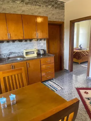 a kitchen with a table and a sink and a bed at Flat in Kom in Luxor