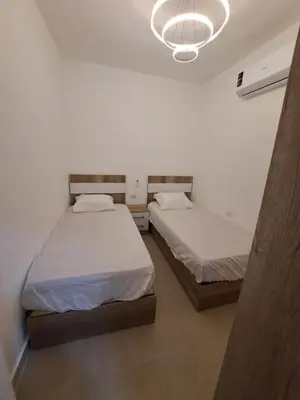 a bedroom with two beds and a chandelier at Beach front 2BR at elkarma hotel & aqua park in Hurghada