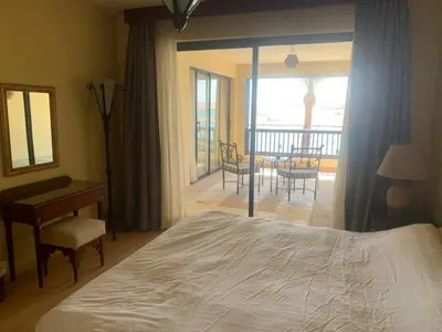 a bedroom with a bed and a desk and a balcony at Marina Bliss-Seaside Retreat in Marsa Alam