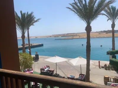 a balcony with a view of a beach with palm trees at Marina Bliss-Seaside Retreat in Marsa Alam