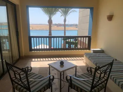 a balcony with two chairs and a table and a window at Marina Bliss-Seaside Retreat in Marsa Alam