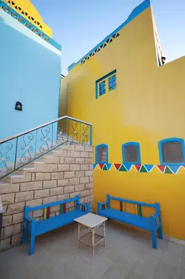a yellow building with blue benches and a staircase at Nubiano Cataract in Shellal