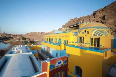 a group of yellow and blue buildings next to a river at Nubiano Cataract in Shellal