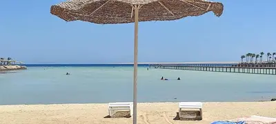 a beach with two chairs and an umbrella on the beach at منتجع سكانديك in Hurghada