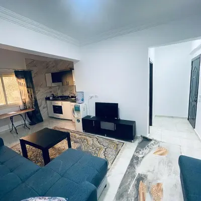 a living room with a blue couch and a kitchen at 1 plus 1 in city centre Hurghada in Hurghada