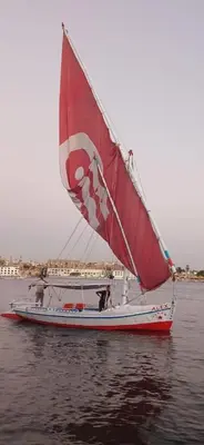a red and white sail boat in the water at Alex in Luxor