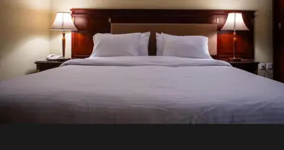 a large bed with white sheets and pillows and two lamps at Fantasy home in Al Aqālitah