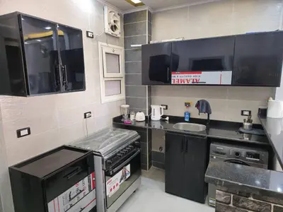 a small kitchen with black cabinets and a sink at El Hadaba behind Raya in Hurghada
