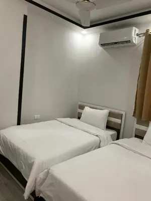 two beds in a room with white sheets and a fan at El Hadaba behind Raya in Hurghada
