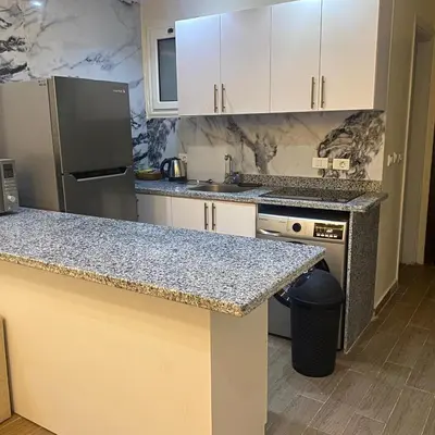 a kitchen with white cabinets and a granite counter top at Luxury Sea View Studio at Alsaraya Resort Your Ultimate Sahl Hasheesh Getaway in Hurghada