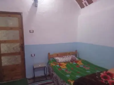 a bedroom with a bed with a green comforter at Nubian dream house in Jazīrat Fīlah