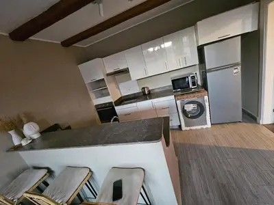 a kitchen with white cabinets and a counter with chairs at Luxury one bedroom in Hurghada
