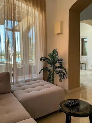a living room with a couch and a palm tree at Luxury villa west golf in Hurghada