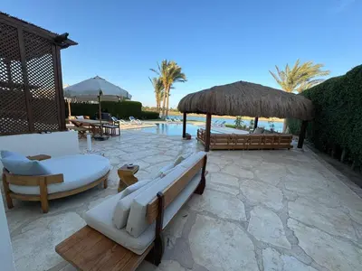 a patio with couches and umbrellas and a pool at Luxury villa west golf in Hurghada