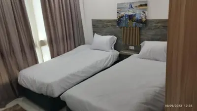 two beds in a hotel room with white sheets at Fanadir Bay Resort in Hurghada