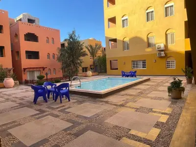 a pool in a courtyard with blue chairs and buildings at Amazing 2BR Apartment - Al Dora Resort, Hurghada in Hurghada