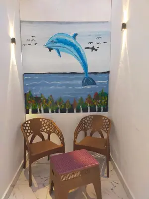 a room with two chairs and a painting of a dolphin at Dolphin guest house in Jazīrat al ‘Awwāmīyah