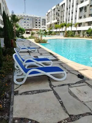 a row of chaise lounge chairs next to a swimming pool at Fanadir Bay Resort in Hurghada