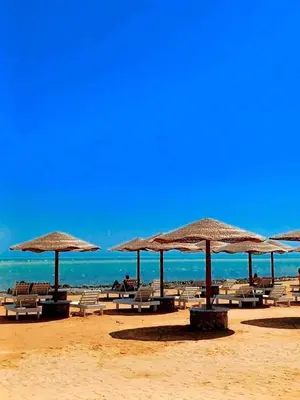 a beach with chairs and umbrellas and the ocean at Fanadir Bay Resort in Hurghada