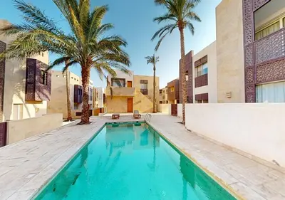a swimming pool with palm trees and a building at Stylish 1 Bedroom at Scarab - El-Gouna WS14 in Hurghada