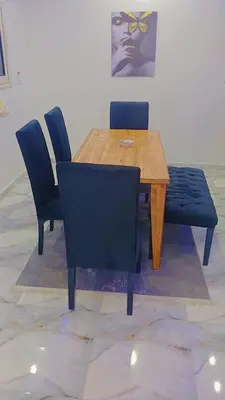 a wooden table with two chairs and a blue bench at Memo home in Jazīrat al ‘Awwāmīyah