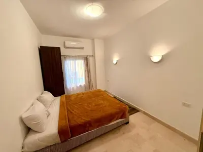 a bedroom with a bed with a brown blanket on it at Stunning 2BR Apartment - Al Dora Resort, Hurghada in Hurghada