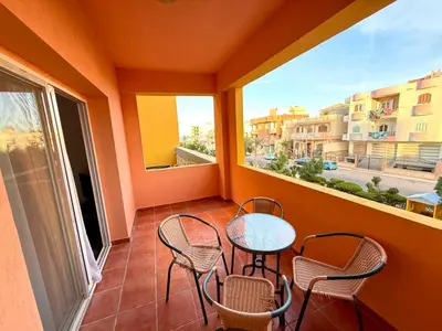 a balcony with chairs and a table and a window at Stunning 2BR Apartment - Al Dora Resort, Hurghada in Hurghada