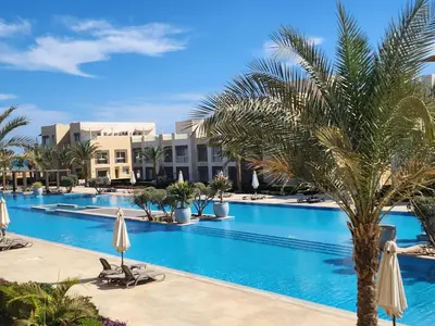 a pool at the resort with palm trees and umbrellas at Elgouna - Mangroovy 2BR - Pool & Sea view in Hurghada