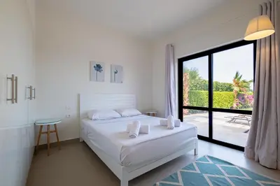 a white bedroom with a bed and a large window at Fanadir 3BR • Prime Sea View Villa in Hurghada