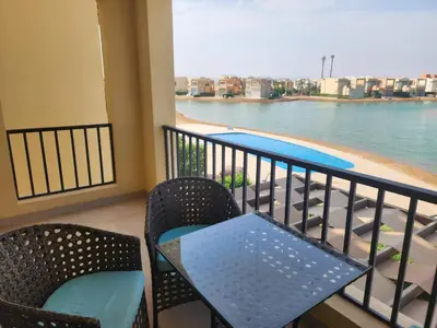 a balcony with a table and chairs and a swimming pool at Gouna - Tawila 1BR breathtaking lagoon & pool view in Hurghada