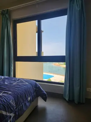 a bedroom with a large window with a view of the ocean at Gouna - Tawila 1BR breathtaking lagoon & pool view in Hurghada