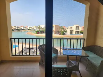 a balcony with a table and chairs and a view of the water at Gouna - Tawila 1BR breathtaking lagoon & pool view in Hurghada