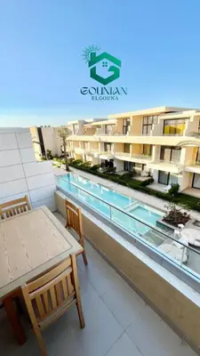 a balcony with a table and a swimming pool at Cozy studio G-cribs in Hurghada