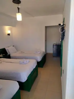 a room with three beds and a door to another room at New Geisum Resort in Hurghada