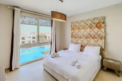 a bedroom with a bed and a large window at Radiant & Refined 2BDR MangroovyFree Beach & Pool in Hurghada