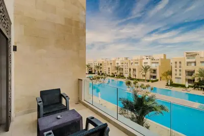 a balcony with a view of a pool and buildings at Radiant & Refined 2BDR MangroovyFree Beach & Pool in Hurghada