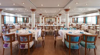 a dining room with white tables and chairs at Acamar Nile Cruise - Every Monday from Luxor for 04 & 07 Nights - Every Friday From Aswan for 03 & 07 Nights in Luxor