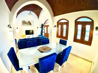 a dining room with a white table and blue chairs at Villa 3bedroom in new years in Hurghada