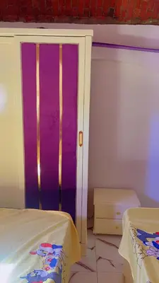 a room with a bed and a purple wall at waleed home in Jazīrat Aswān