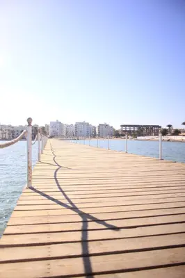 a shadow of a person on a pier in the water at سكانديك ريزورت - Scandic resort in Hurghada