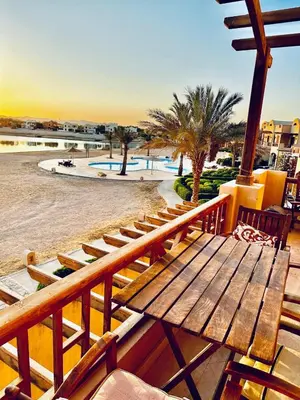 a wooden bench sitting on a balcony next to a pool at 2Bedroom in west golf in Hurghada