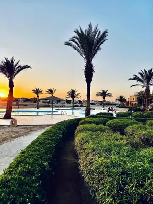 a path next to a beach with palm trees at 2Bedroom in west golf in Hurghada
