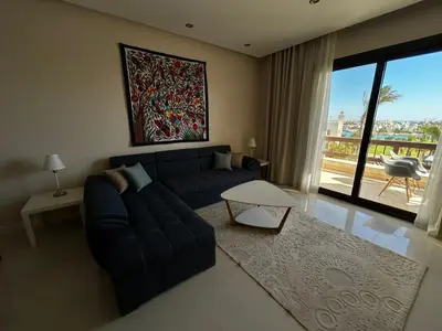 a living room with a blue couch and a large window at luxury ancient stands resort one bedroom in Hurghada