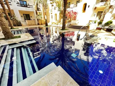 a reflection of a pool in a building with palm trees at luxury ancient stands resort one bedroom in Hurghada