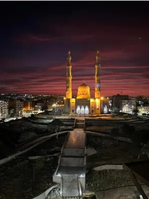 a large building with a mosque at night at City center NewAswan in Aswan