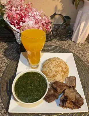 a plate with meat and rice and a glass of juice at City center NewAswan in Aswan