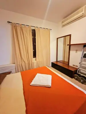 a bedroom with a bed with an orange blanket and a mirror at bedroom in west golf 1 in El Gouna