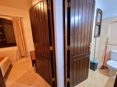 a bathroom with two wooden doors and a toilet at bedroom in west golf 1 in El Gouna