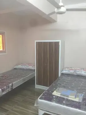 a room with two beds and a wooden cabinet at اسوان كسر الحجر وسط البلد in Aswan